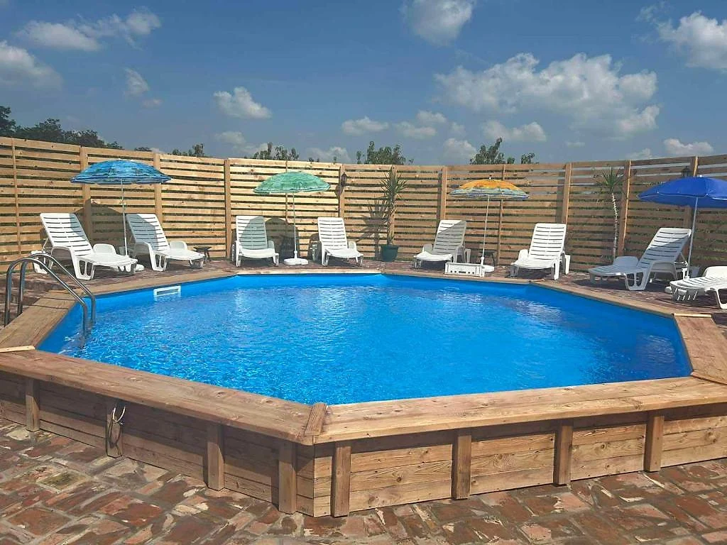 Drveni bazen sa belim ležaljkama i suncobranima u dvorištu etno sela
